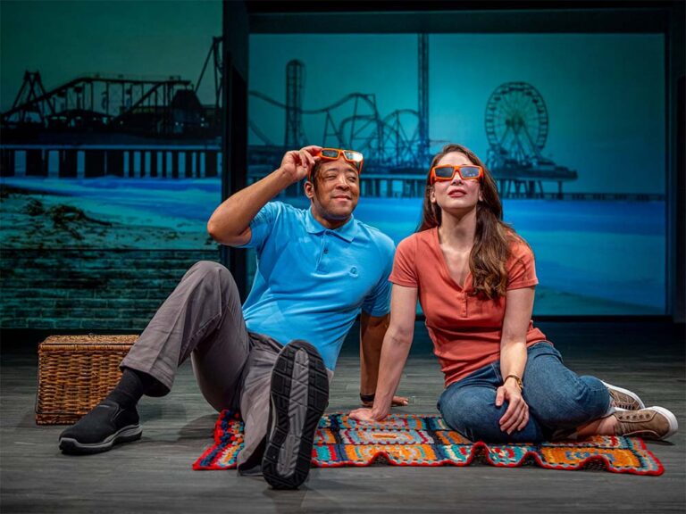 Two actors one man and one woman sitting down and looking up at the sky